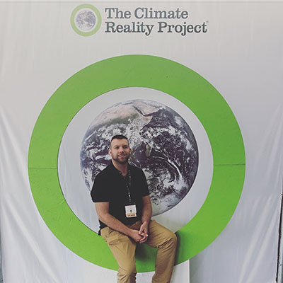 Sean Gray, ESP student sits in front of The Climate Reality Project banner at his recent training experience. 
